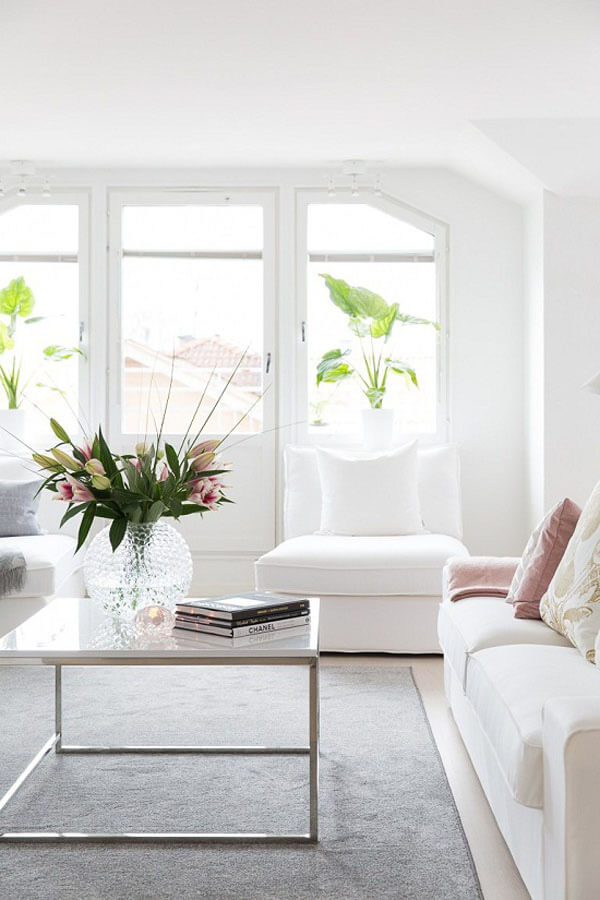 Thiết kế nội thất nhà chung cư với phòng khách trang nhã với bộ sofa trắng, điểm màu hồng pastel của gối tựa hay hoa tươi khiến không gian trở nên sinh động.